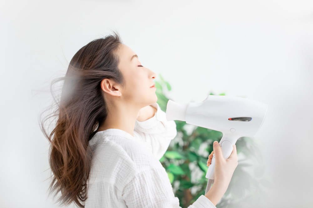 ドライヤーで髪を乾かす女性