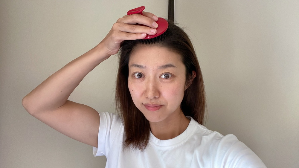 マッサージブラシで頭皮ケアをする女性